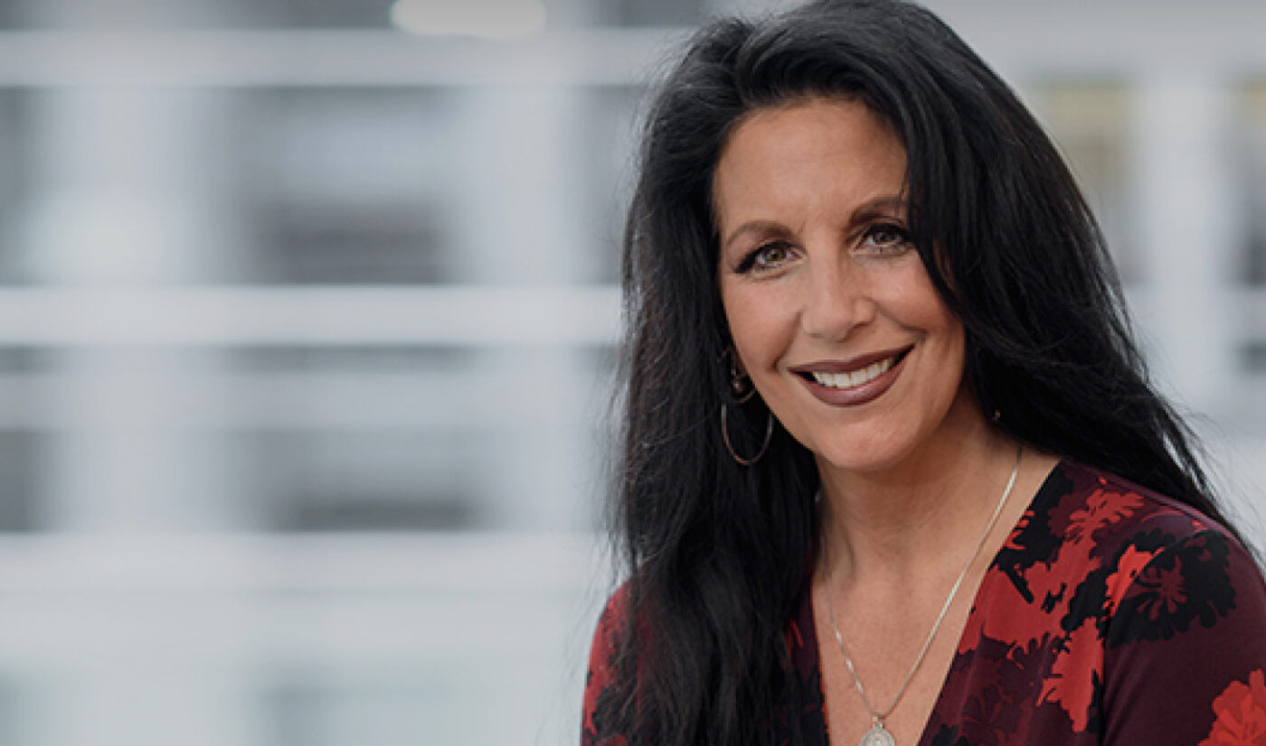 Woman with long dark hair sits in front of window